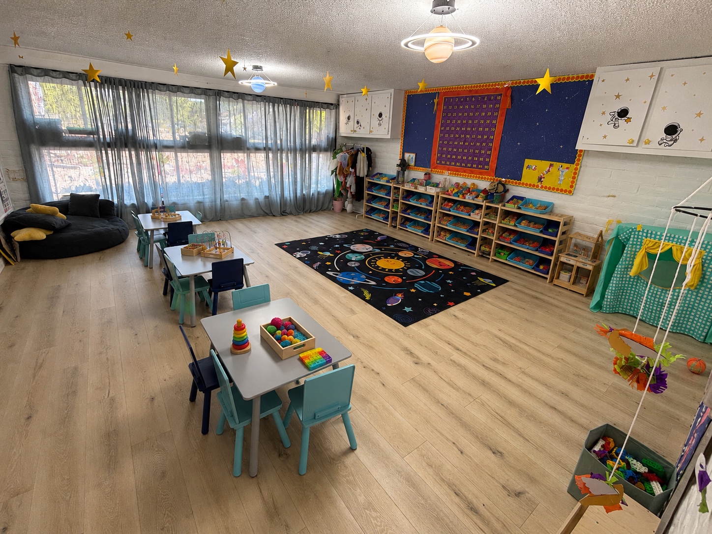 Space-themed classroom with solar system rug, stars and learning shelves